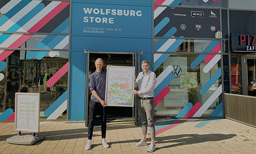 Jonas Lamberg und Christoph Kaufmann präsentieren das Buch „Glücksorte in und um Wolfsburg“ vor dem Wolfsburg Store